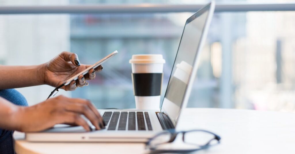 pexels-photo-1181248-1181248 Close-up of hands using a laptop and phone with coffee on a modern office desk.